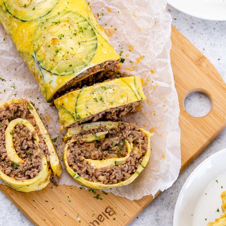 an omelet filled with meat and vegetables on a cutting board next to other food items