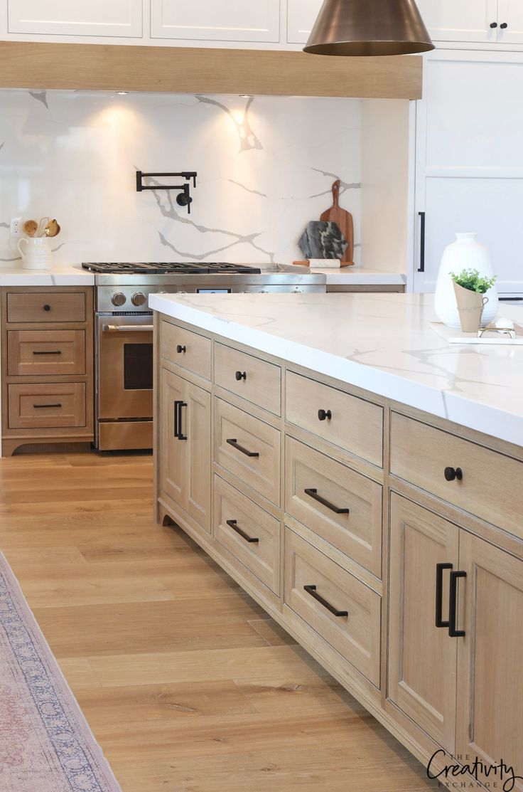 a large kitchen with white cabinets and wood flooring is seen in this image from the front view