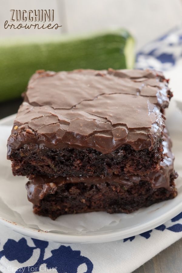 two pieces of chocolate cake sitting on top of a plate next to a cucumber