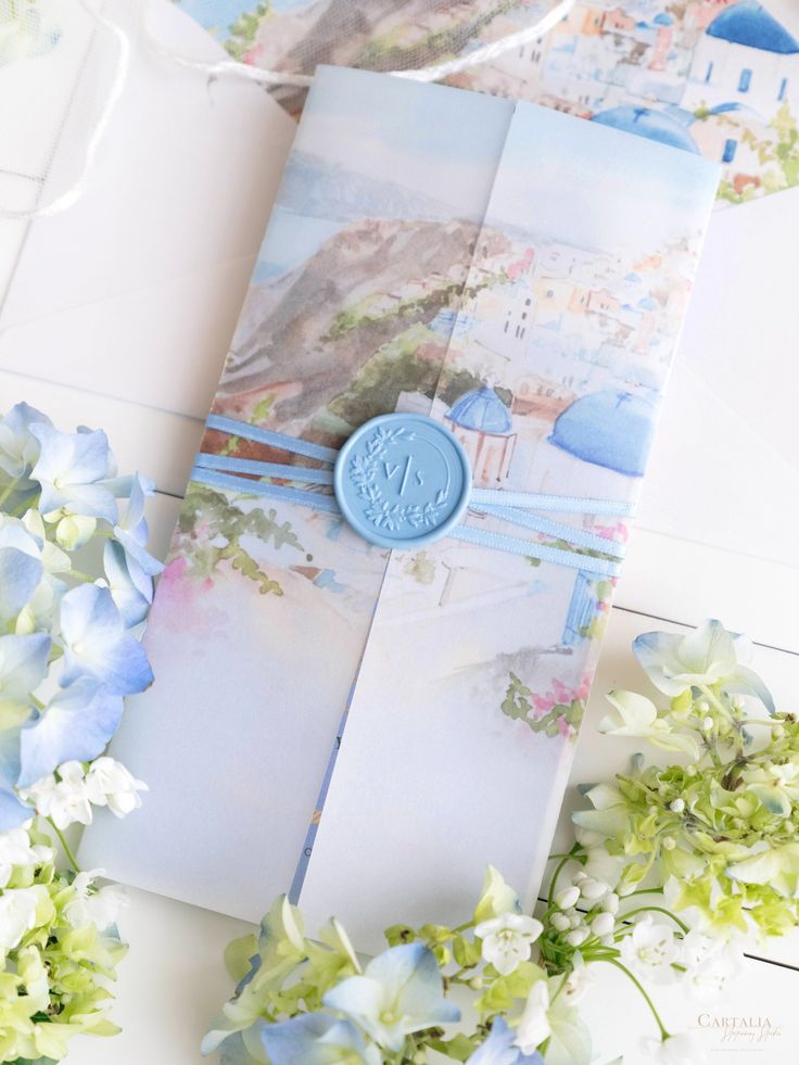 an open book with blue buttons on it and flowers in the foreground, along with other items