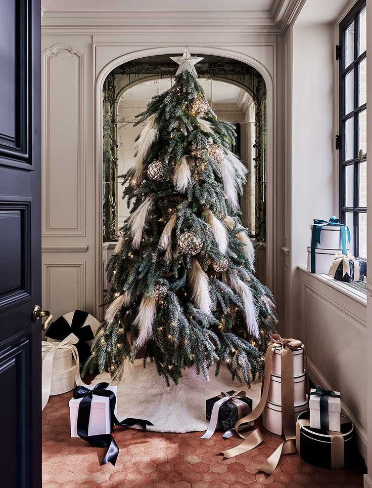 a decorated christmas tree in the corner of a room with black and white ribbons on the floor