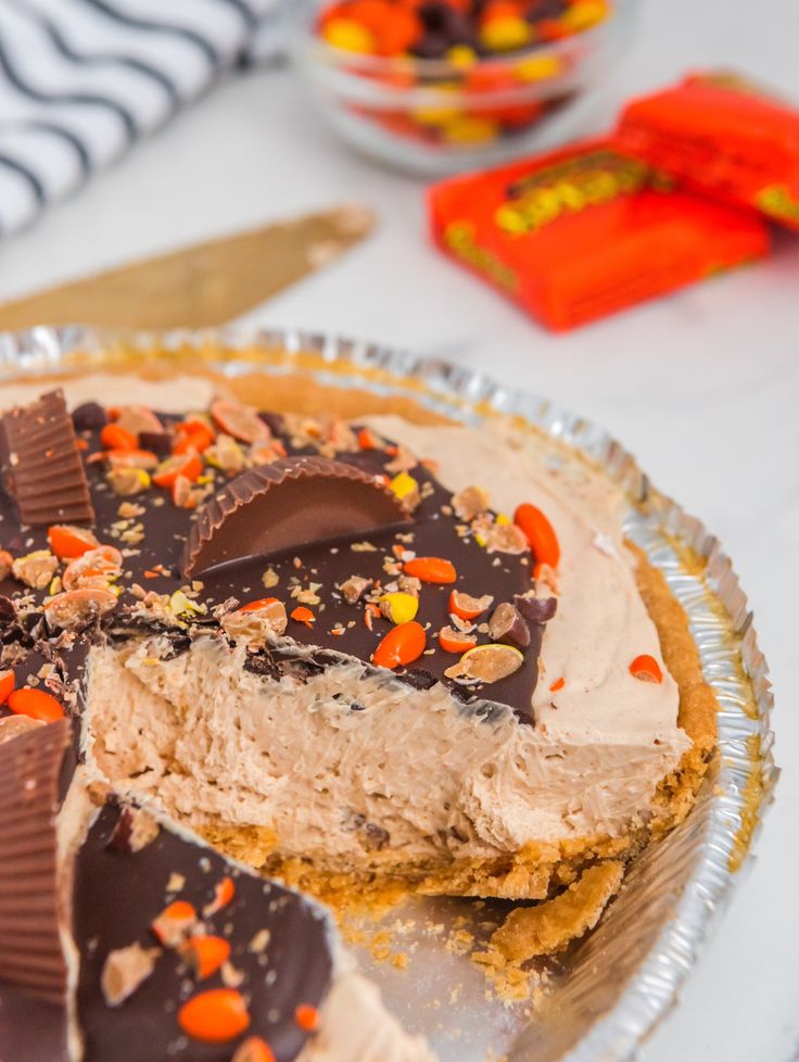 there is a pie with chocolate and candy toppings on the top, ready to be eaten