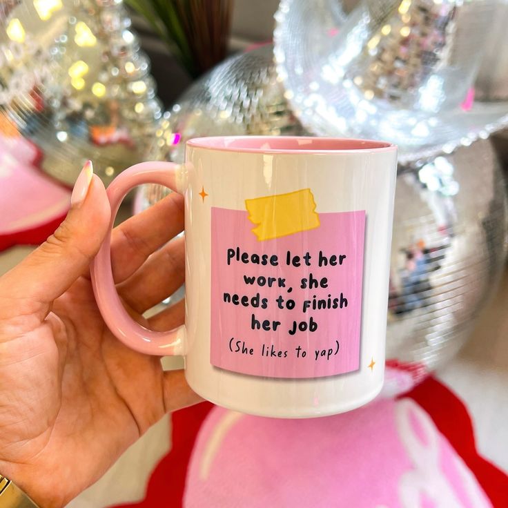 a person holding a pink coffee mug with a quote on the front and inside it