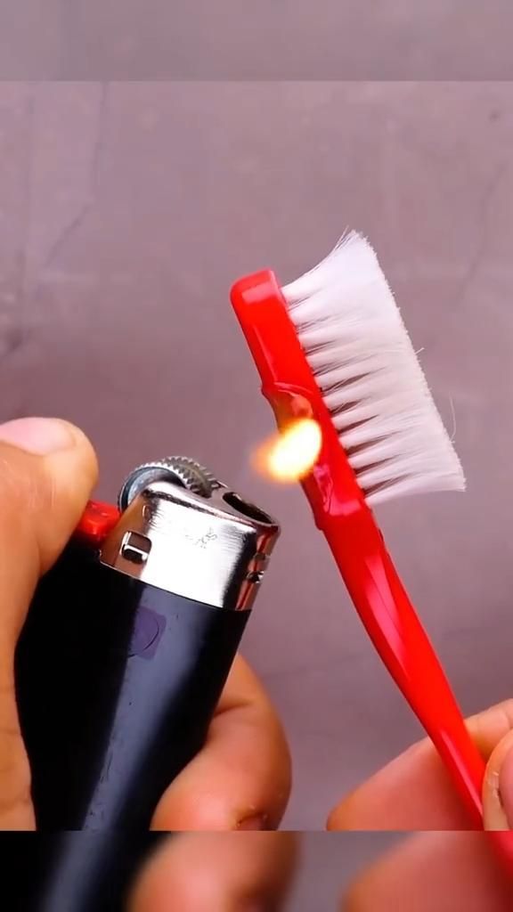 a person holding a lighter with a toothbrush in it