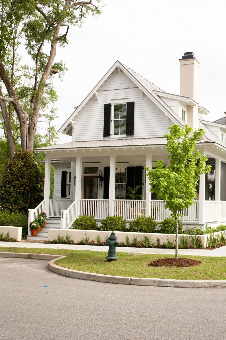 a white house with black shutters and a green fire hydrant in the front yard