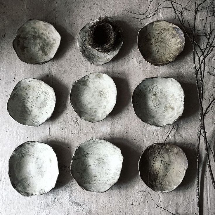 nine cement balls sitting on top of a concrete floor next to plants and twigs in front of them