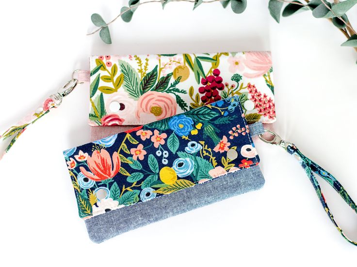 three wallets are lined up next to each other on a white surface with flowers and leaves