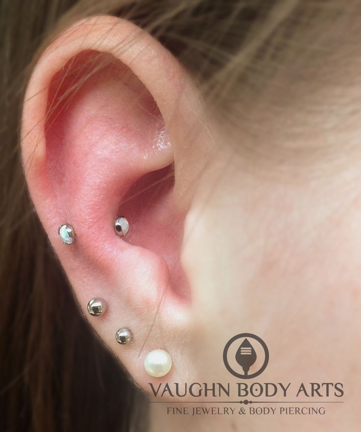 a woman's ear with three different piercings on the top and bottom of it