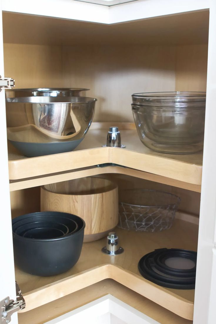 an open cabinet with bowls and plates on it