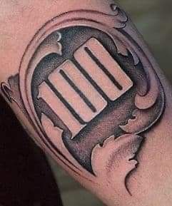 a man's arm with a black and grey tattoo design on it, which has the letter m in an oval shape