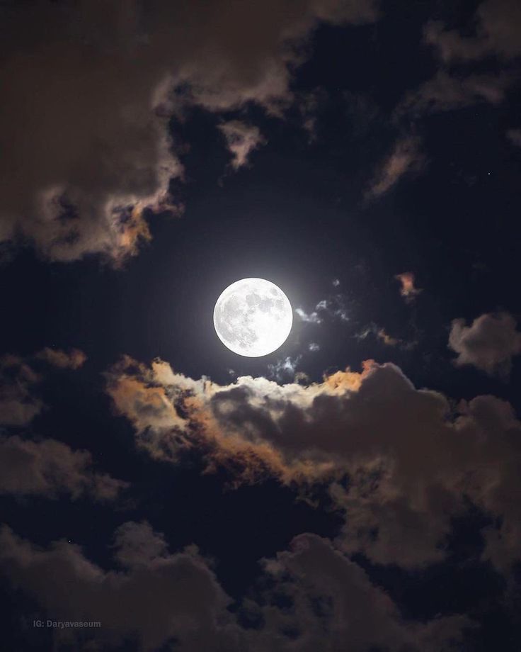 the full moon is seen through some clouds