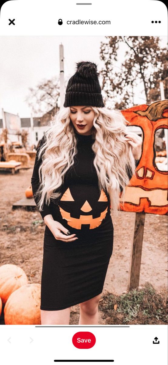 a woman in a black dress and hat standing next to pumpkins with her hands on her hips