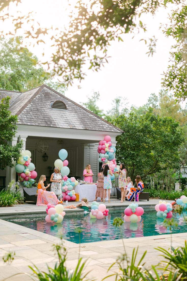 a group of people standing around a pool filled with balloons