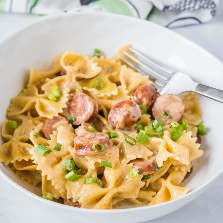 a white bowl filled with pasta and sausage