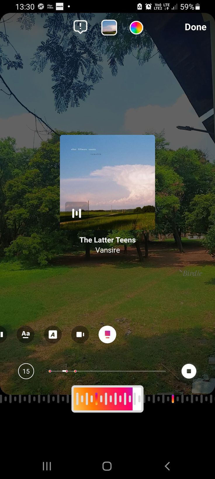 the camera app is open and showing an image of a grassy field with trees in the background