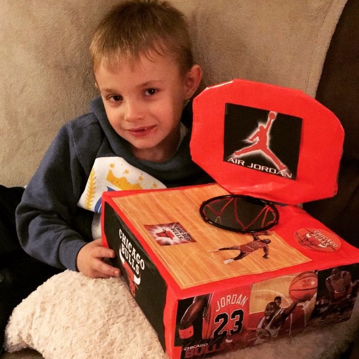 a young boy sitting on a couch holding a box with basketball memorabilia in front of him