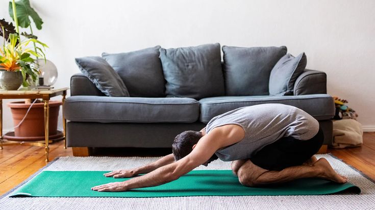 a man is doing yoga on a mat in front of a couch and coffee table