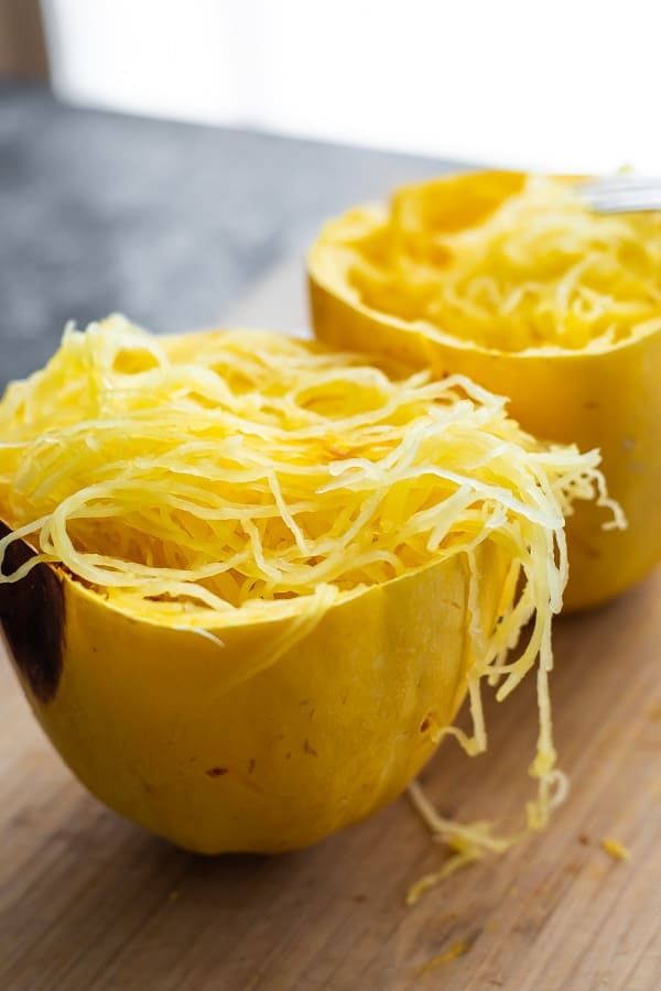 two yellow squash halves with shredded cheese in them