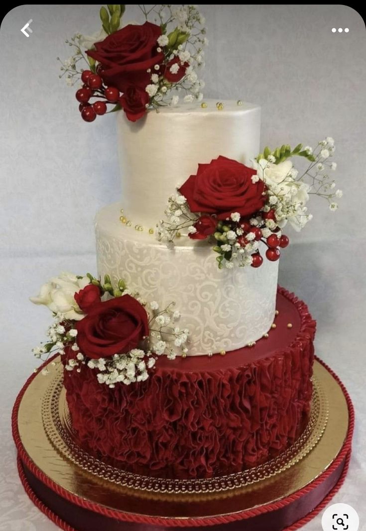 a three tiered wedding cake with red roses on top