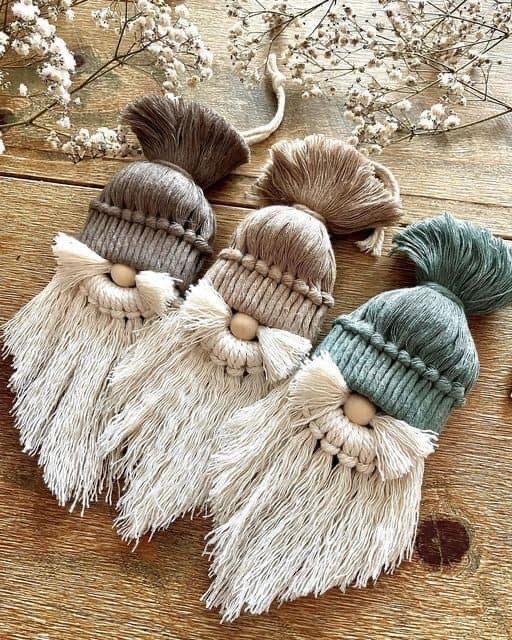 three knitted hats with tassels are sitting on a wooden table next to flowers