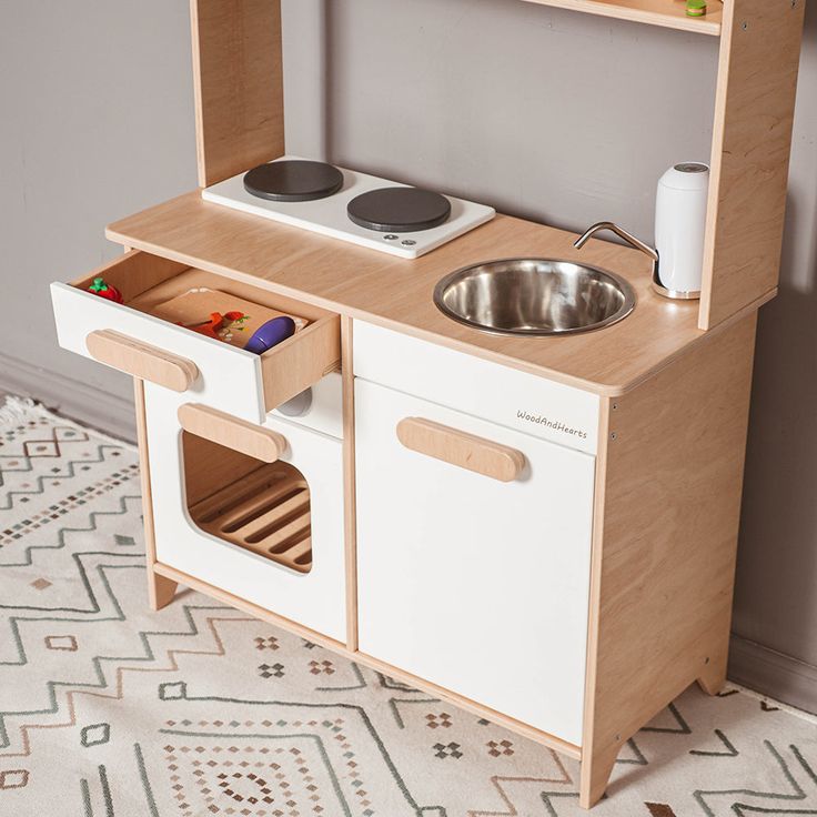 a child's play kitchen with sink, stove and cupboards on the floor