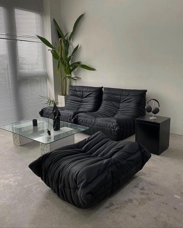 a living room with black furniture and a glass table