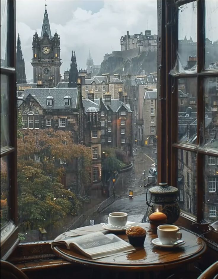 a table with two cups and saucers on it in front of an open window