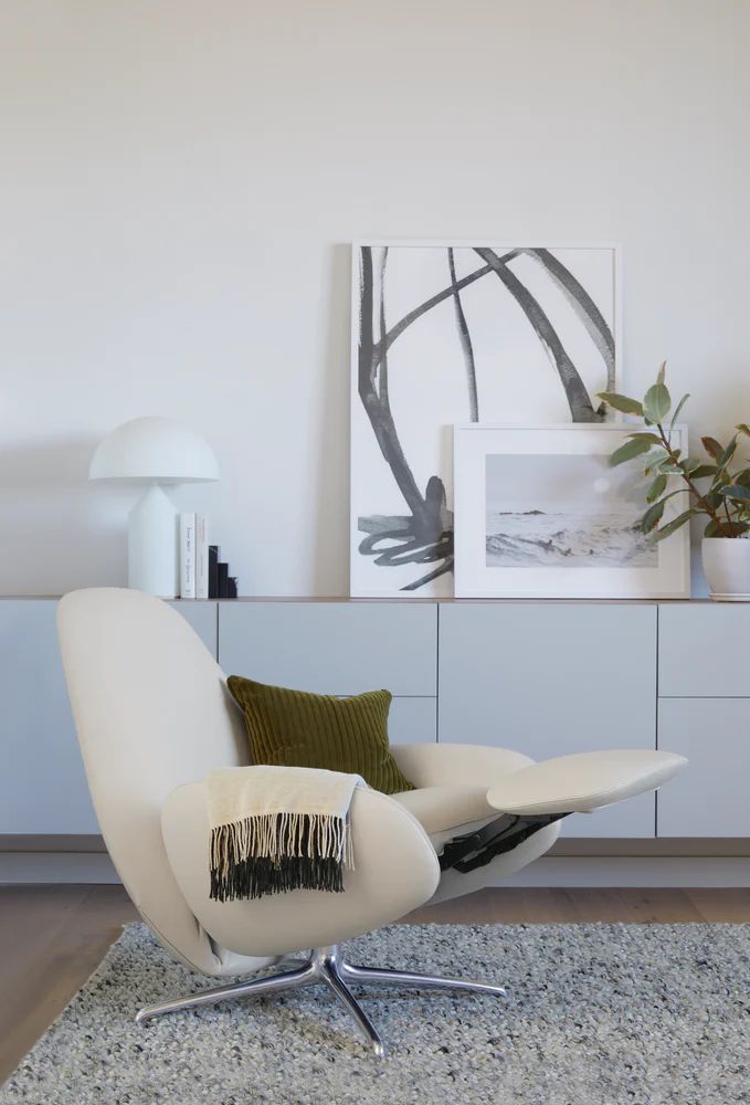 a white chair sitting on top of a rug in a living room next to a wall