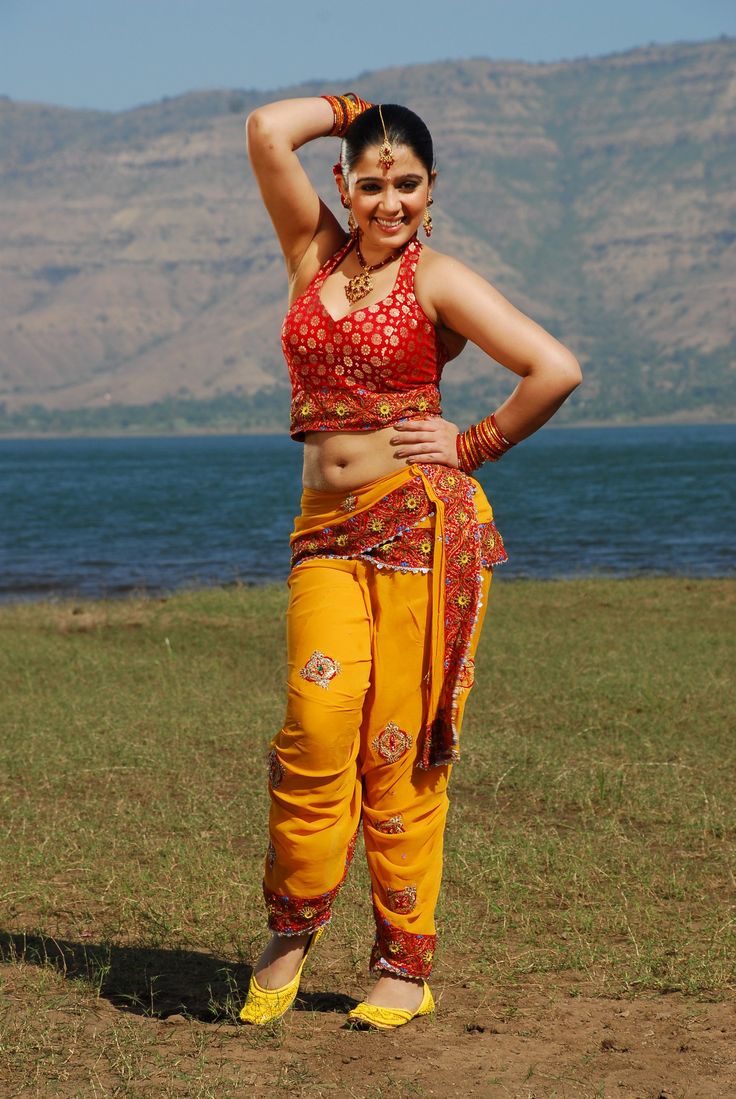 a woman in yellow pants and red top posing for the camera with her hands on her head