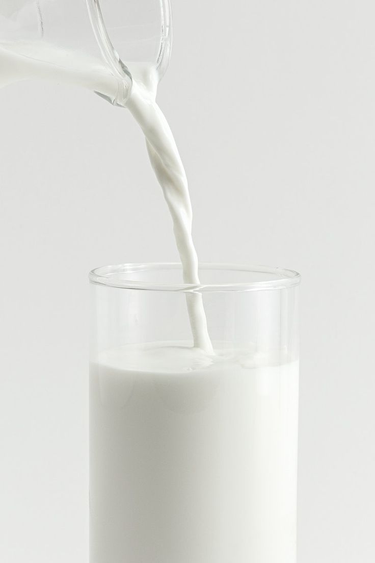 a glass filled with milk being poured into it