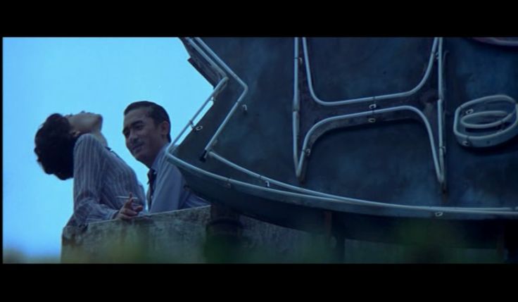 a man and woman standing next to each other near a giant metal object in the sky