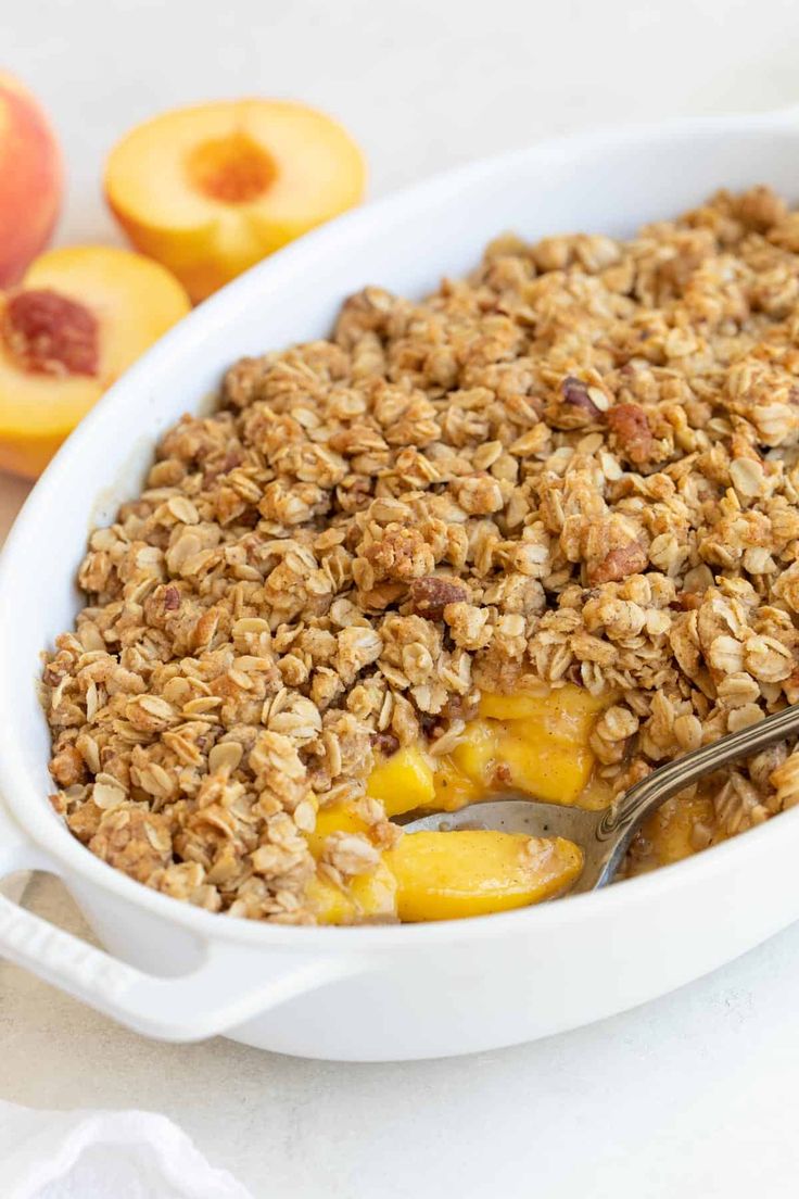 a white dish filled with granola and peaches