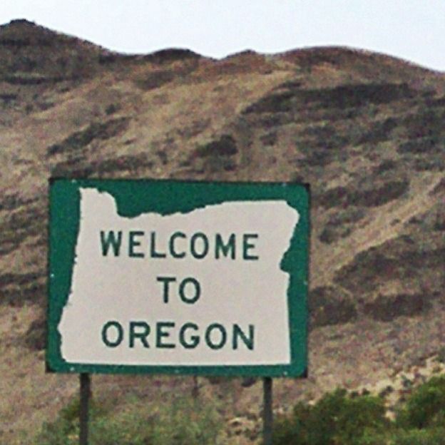 a welcome to oregon sign in front of a mountain