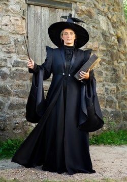 a woman dressed in black holding a book and wearing a large hat with long sleeves