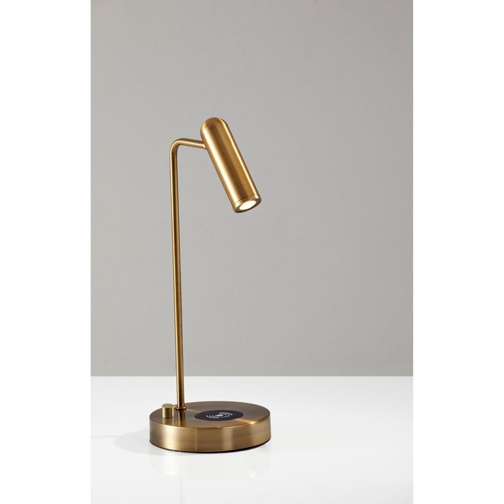 a gold desk lamp sitting on top of a white table