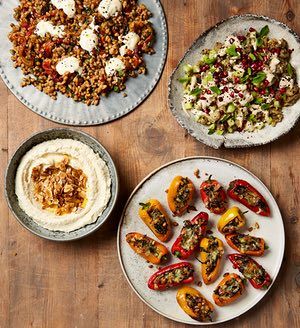 four plates with different foods on them sitting on a wooden table next to each other