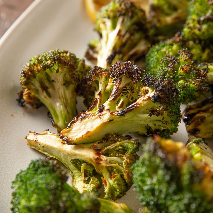 broccoli florets on a white plate with lemon wedges in the background