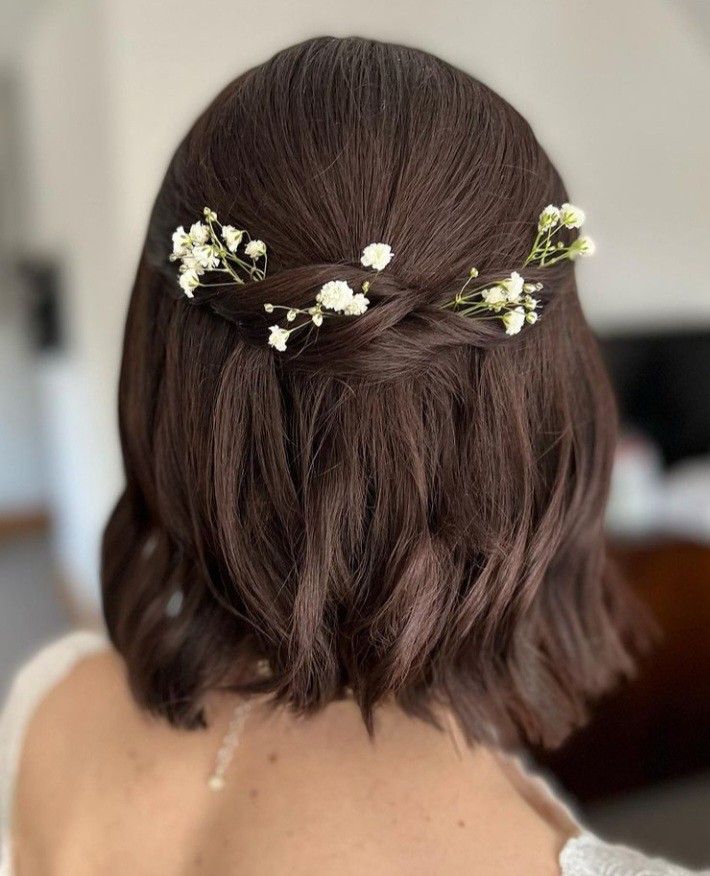 the back of a woman's head with white flowers in her hair, wearing a bridal hairstyle