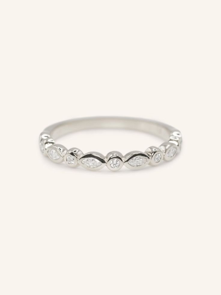 a white gold ring with three diamonds on the top, and two rows of leaves in the middle