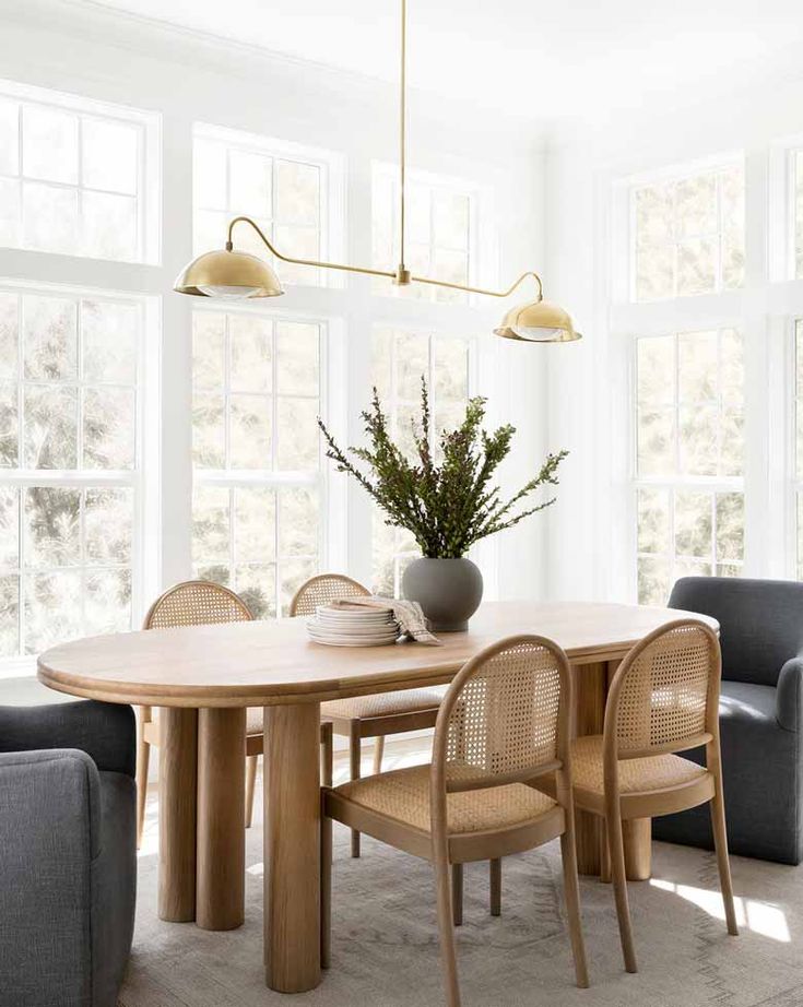 a dining room table with chairs and a vase filled with flowers on top of it