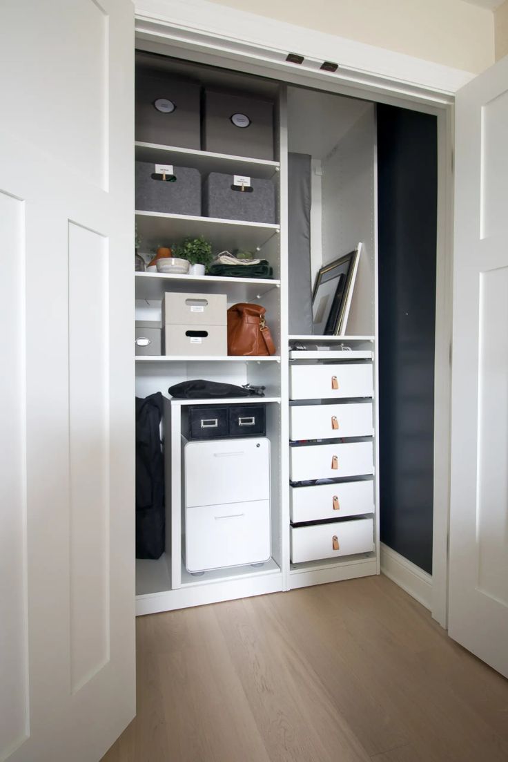 an open closet with white drawers and black walls