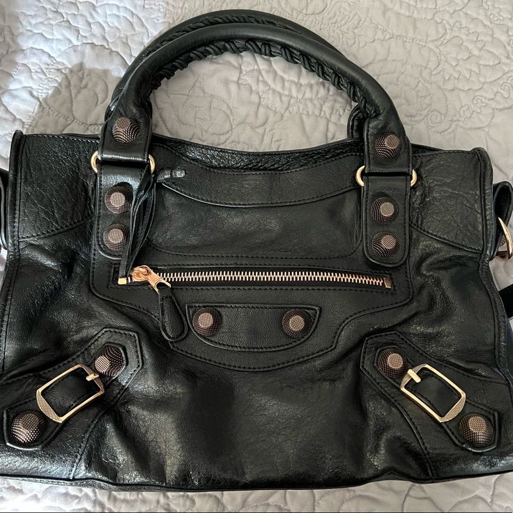 Rare Find: Balenciaga City Giant Studs Bag - Medium With Rose Gold Hardware. Black Leather With Rose Gold Hardware. Prestine Preloved Condition. No Major Damage, Clean Throughout. Minor Wear On Bottom Edges (See Picture). Comes With Dust Bag. Dimensions 15”Wx9.5”Hx5”D 6” Handle Drop 12” Strap Drop Bags Balenciaga, Studded Bag, Rose Gold Hardware, Balenciaga City Bag, Medium Bags, Gold Hardware, Balenciaga, Satchel, Dust Bag