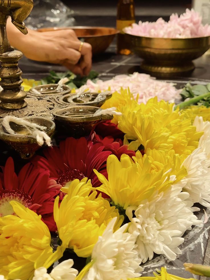 flowers are laid out on a table with an oil lamp in the middle and two bowls behind them