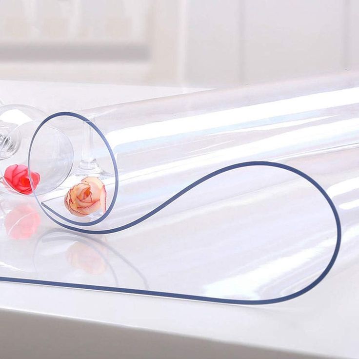 two wine glasses sitting on top of a white table next to a red rose in a clear tube