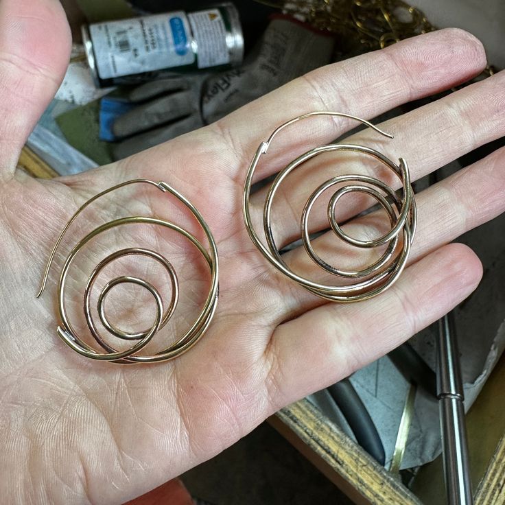 I am always on the quest to figure out a new shape out of a single wire. These whirlwind earrings are made of a looped and fabricated .8mm round wire. They are light, interesting and unique hoop for those people that don't like posts. About 1.75" in diameter, made in brass and finished in 14k nickel free gold plate. You are also welcome to order them in silver! Spiral Earrings With A Modern Twist, Modern Twist Round Earrings, Handmade Swirl Jewelry With A Modern Twist, Modern Twist Round Metal Earrings, Spiral Brass Hoop Earrings With Ear Wire, Modern Twist Nickel Free Hoop Earrings, Modern Twist Nickel-free Hoop Earrings, Nickel-free Round Earrings With A Modern Twist, Metal Spiral Wrap Single Earring