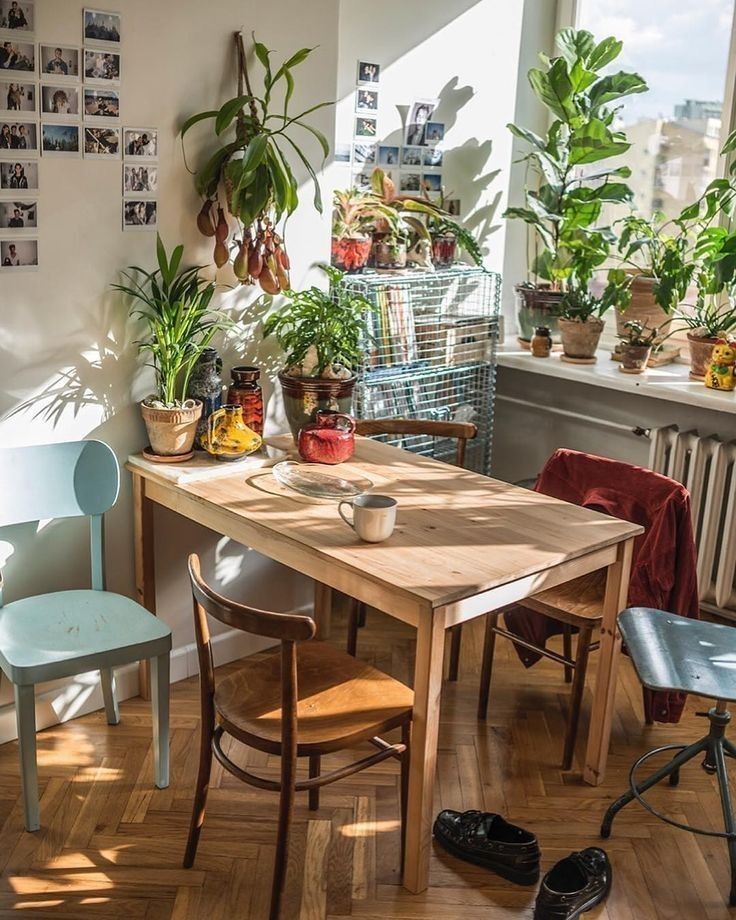 a wooden table surrounded by chairs and potted plants