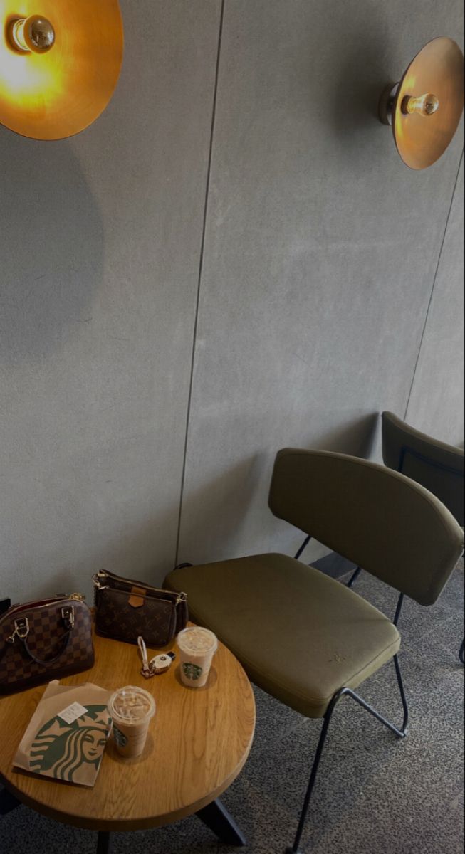 two chairs and a table in a room with light fixtures on the wall behind them