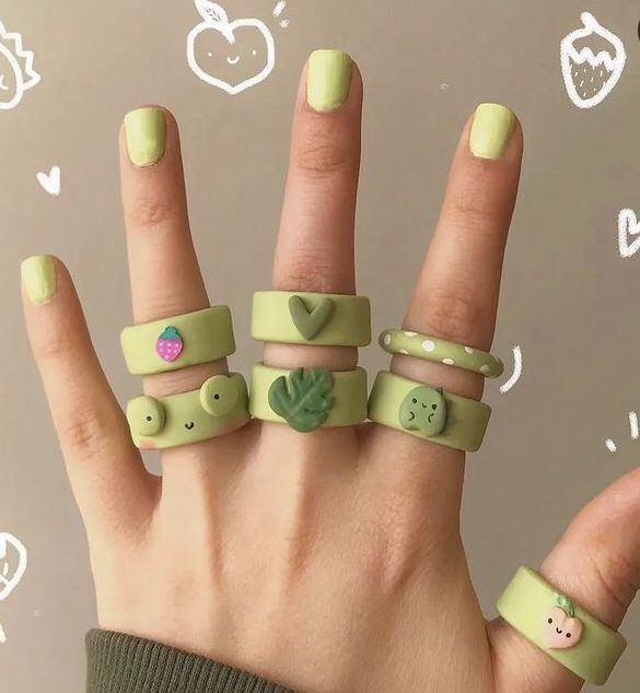 a person's hand with four different rings on it and two fingers that have faces painted on them