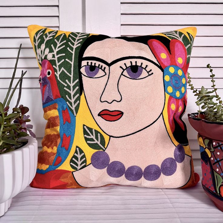 a decorative pillow with a woman's face on it next to potted plants