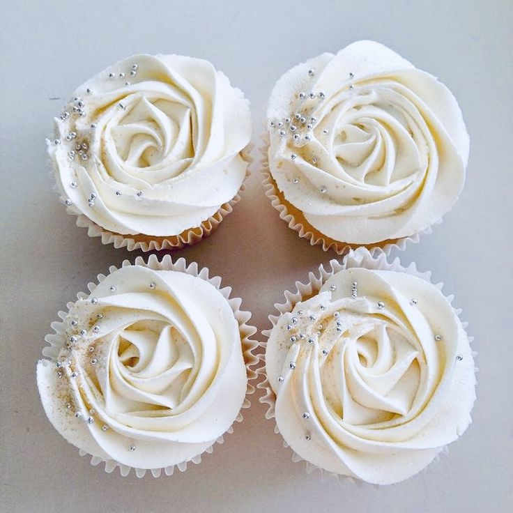 four cupcakes with white frosting and crystal decorations on them are arranged in the shape of a rose